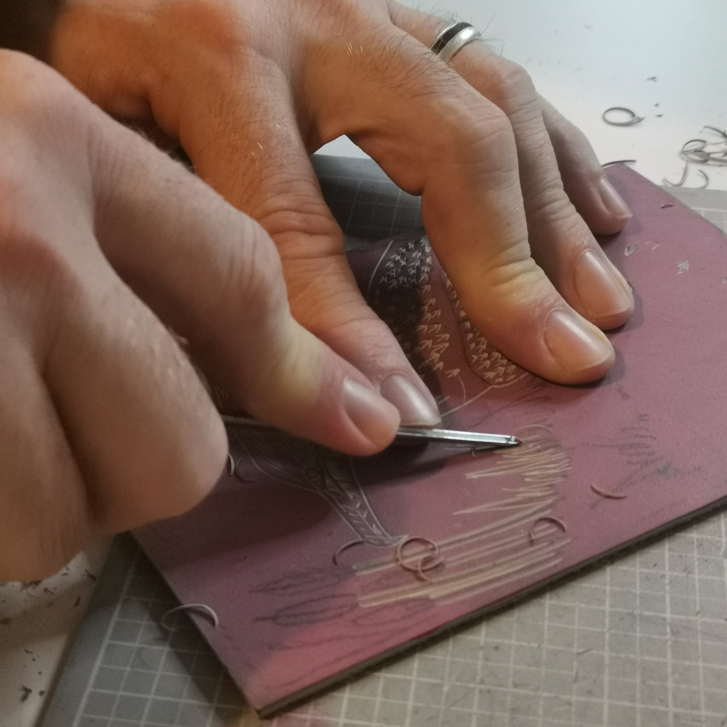 Close up of Hands using carving tool to carve details into lino block for art prints