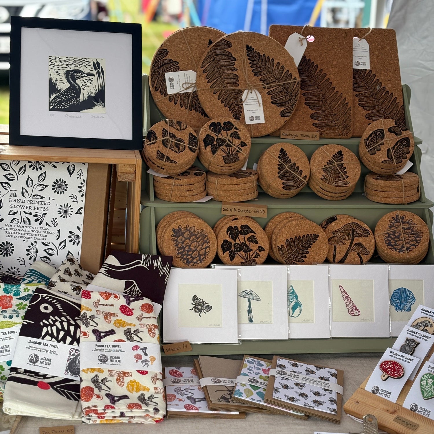 Display of cork printed coasters, prints, and cards at an outdoor market stall.