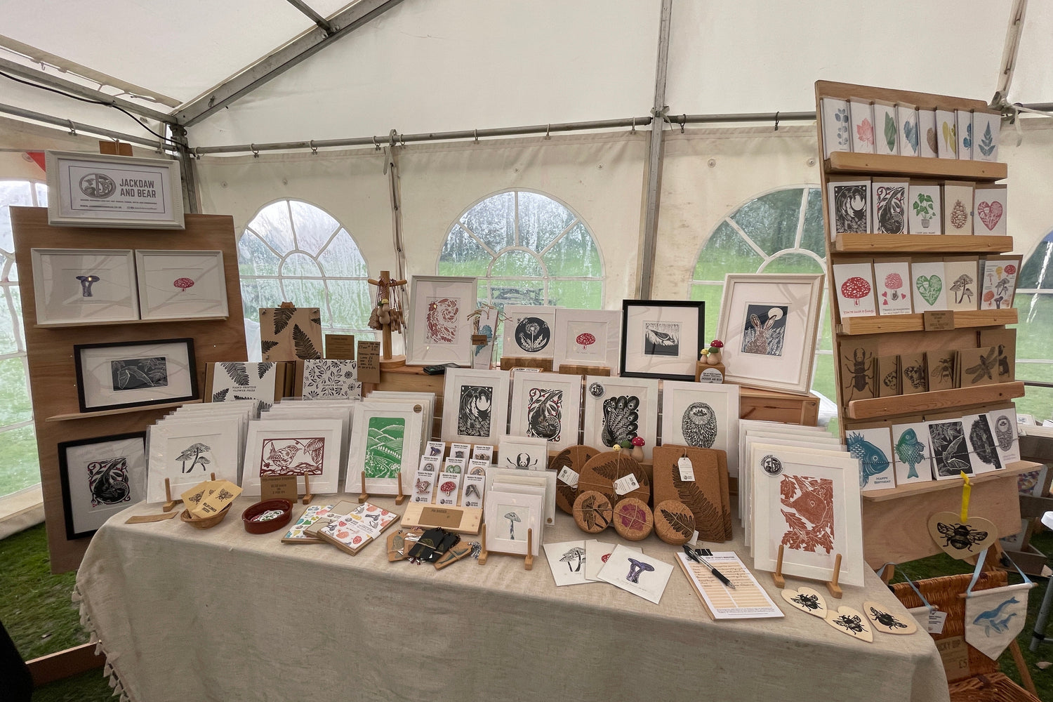 Table displaying autumn inspired framed and mounted artworks under a marquee
