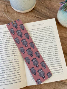 Repeat pattern Owl design on dusky pink background bookmark- features linocut design print. Bookmark resting across a paperback book with coffee mug and plant in background